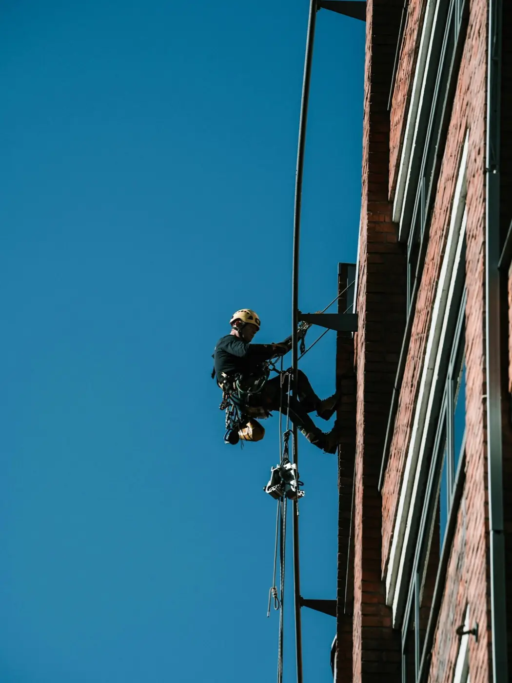 Técnico de trabajos verticales sobre una fachada de ladrillo